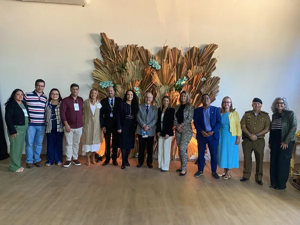 Equipe reunida em frente ao mural do seminário